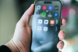 Iphone в руках людини на якому відкрита папка з інструментами ШІ(LLM): Клауд,Чат ГПТ, Діп Сік